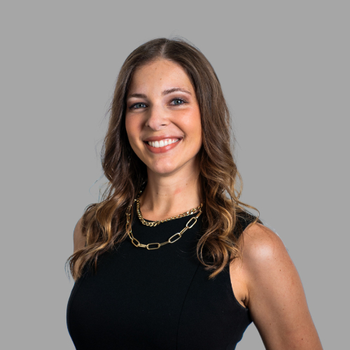 Smiling woman in black dress, gold necklace.