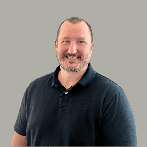 Smiling man in a black polo shirt.